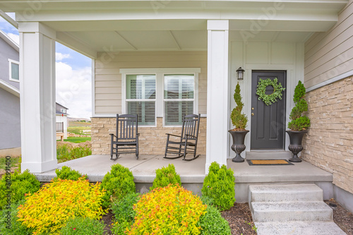 Fototapeta Home facade with stairs leading to porch with pillars and gray door with wreath