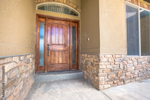 Brown wooden front door of home with sidelights and arched transom window