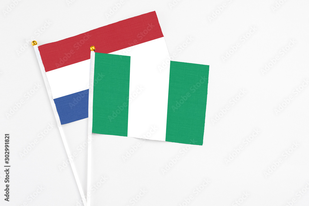 Nigeria and Netherlands stick flags on white background. High quality fabric, miniature national flag. Peaceful global concept.White floor for copy space. Nigeria and Netherlands stick flags on white background. High quality fabric, miniature national flag. Peaceful global concept.White floor for copy space.
