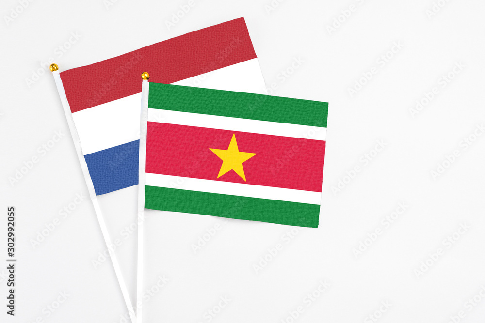 Naklejka premium Suriname and Netherlands stick flags on white background. High quality fabric, miniature national flag. Peaceful global concept.White floor for copy space.