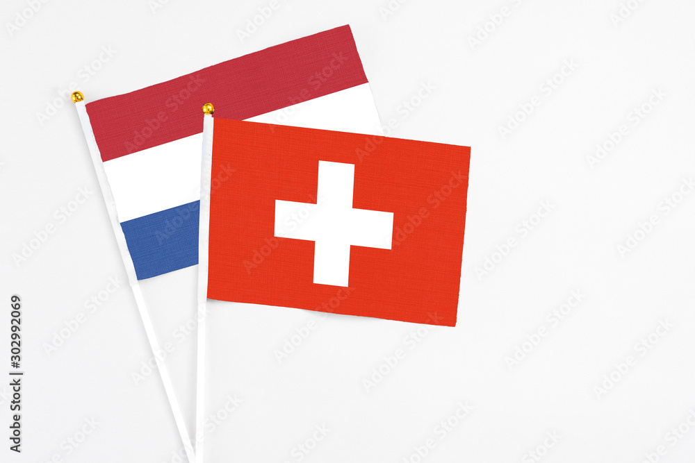 Switzerland and Netherlands stick flags on white background. High quality fabric, miniature national flag. Peaceful global concept.White floor for copy space.