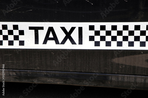 Принти на полотні Taxi logo with checked or chequerboard pattern in black and white, on the side o