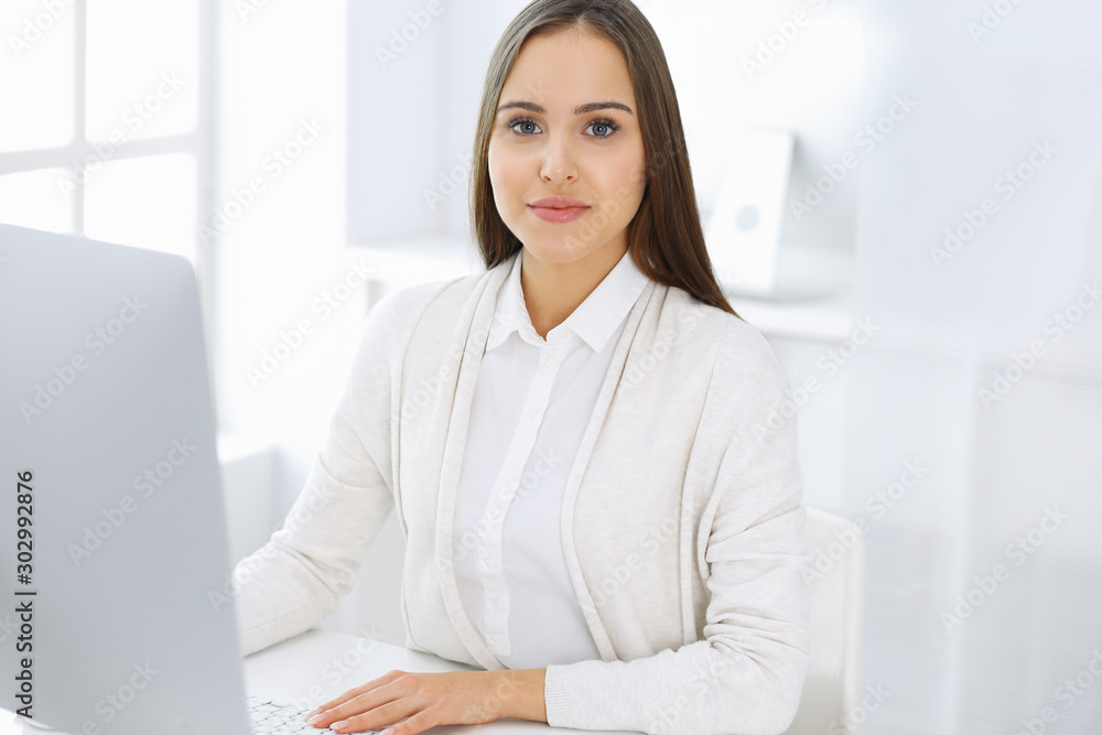 Business woman sitting and working with computer in white office. Student girl studying or secretary making report. Success concept Business woman sitting and working with computer in white office. Student girl studying or secretary making report. Success concept