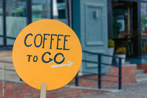 inscription coffee to go on an orange wooden plank. coffee shop, cafe advertisement. takeaway coffee photo