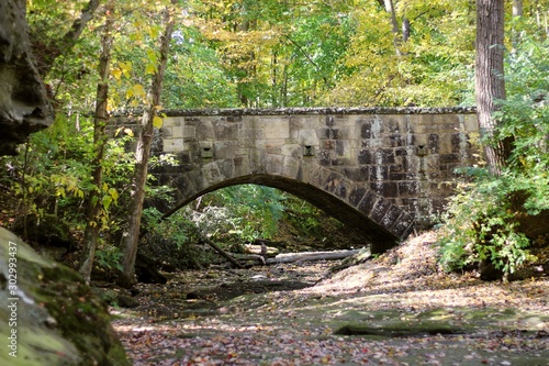 old stone bridge on a warm autumn day in a park setting with big boulder rocks
