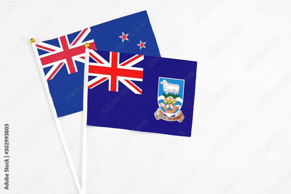 Fototapeta premium Falkland Islands and New Zealand stick flags on white background. High quality fabric, miniature national flag. Peaceful global concept.White floor for copy space.