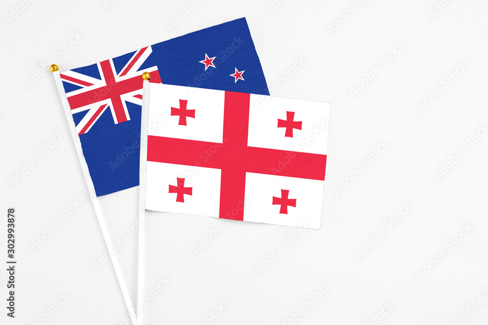Georgia and New Zealand stick flags on white background. High quality fabric, miniature national flag. Peaceful global concept.White floor for copy space.