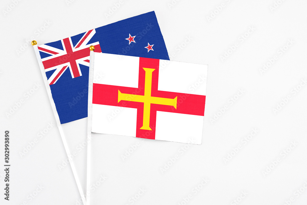 Guernsey and New Zealand stick flags on white background. High quality fabric, miniature national flag. Peaceful global concept.White floor for copy space.