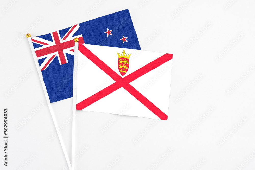 Jersey and New Zealand stick flags on white background. High quality fabric, miniature national flag. Peaceful global concept.White floor for copy space. Jersey and New Zealand stick flags on white background. High quality fabric, miniature national flag. Peaceful global concept.White floor for copy space.