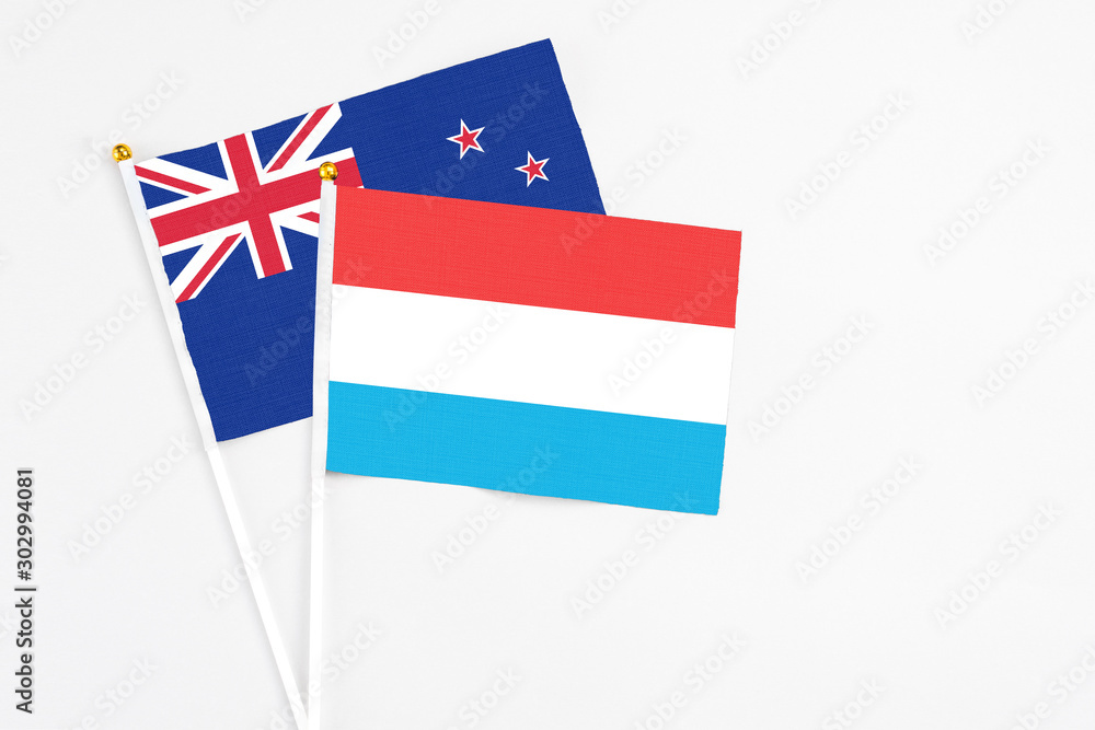 Luxembourg and New Zealand stick flags on white background. High quality fabric, miniature national flag. Peaceful global concept.White floor for copy space. Luxembourg and New Zealand stick flags on white background. High quality fabric, miniature national flag. Peaceful global concept.White floor for copy space.