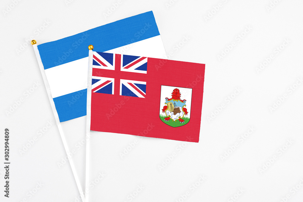 Fototapeta premium Bermuda and Nicaragua stick flags on white background. High quality fabric, miniature national flag. Peaceful global concept.White floor for copy space.