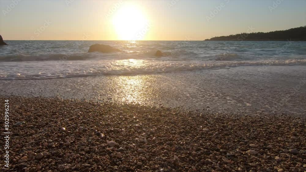 A beautiful beach with pebbles and a rocky shore on the Mediterranean coast in Turkey at sunset. Sea waves A beautiful beach with pebbles and a rocky shore on the Mediterranean coast in Turkey at sunset. Sea waves