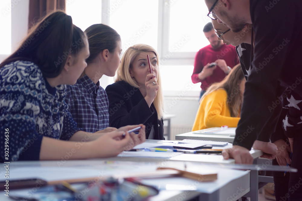 Fototapeta premium Beautiful young female teacher helping a student during class. Female Professor Holding Lecture to Multi Ethnic Group of Students. Smart Young People Studying at the University.