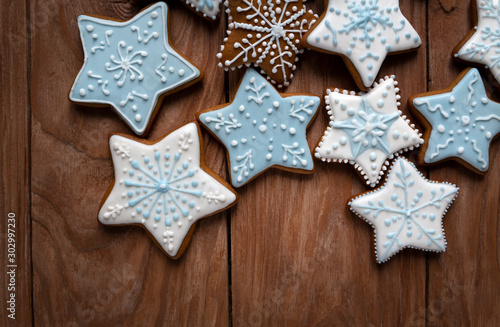 Homemade gingersnaps covered with icing on the wooden background; delicious cookies with Christmas shapes