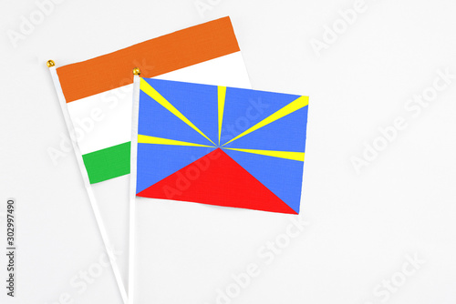 Reunion and Niger stick flags on white background. High quality fabric, miniature national flag. Peaceful global concept.White floor for copy space.