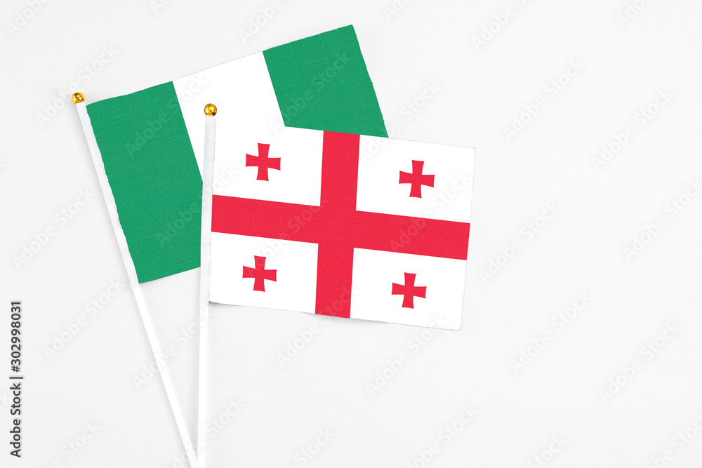 Georgia and Nigeria stick flags on white background. High quality fabric, miniature national flag. Peaceful global concept.White floor for copy space.