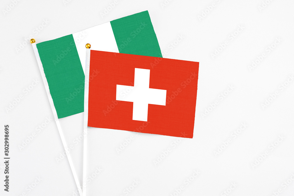 Switzerland and Nigeria stick flags on white background. High quality fabric, miniature national flag. Peaceful global concept.White floor for copy space.