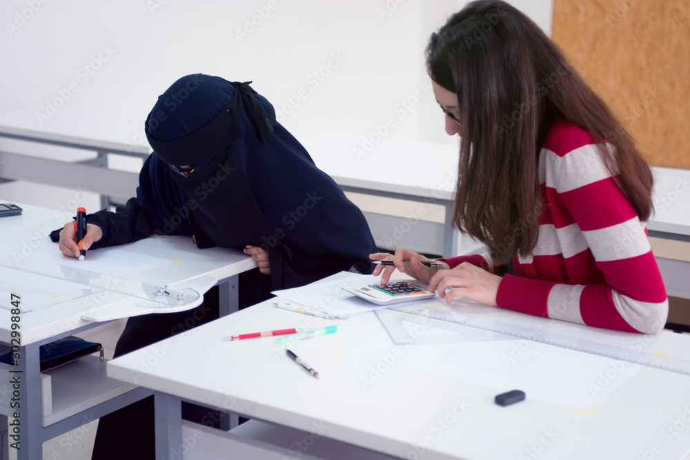 Two female multiethnic university architecture students working on practice lessons. Looking for solution during class. Two female multiethnic university architecture students working on practice lessons. Looking for solution during class.