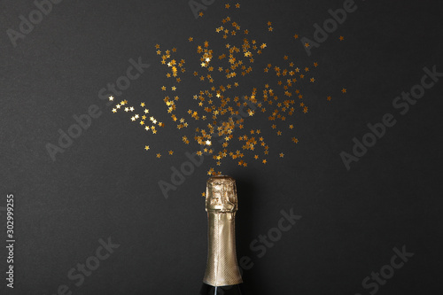bottle of champagne and confetti on a colored background top view. Concept holiday, celebrate, new year, christmas, birthday.