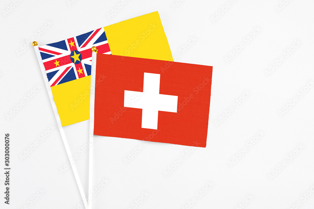Switzerland and Niue stick flags on white background. High quality fabric, miniature national flag. Peaceful global concept.White floor for copy space.
