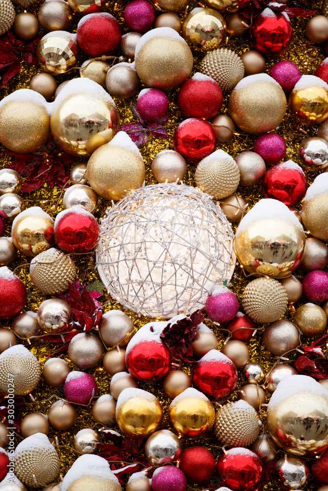 Obraz premium Close-up big New Year's toys balls of different colors with a bright sparkling garland on an artificial Christmas tree. Balls of red, purple and yellow. The concept of the holiday. Selective focus