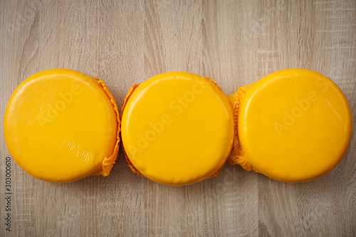 Top view of three heads of organic rustic cheese in a yellow vacuum pakage on a table. Homemade cheese service. The concept of nutrition and healthy lifestyle. photo