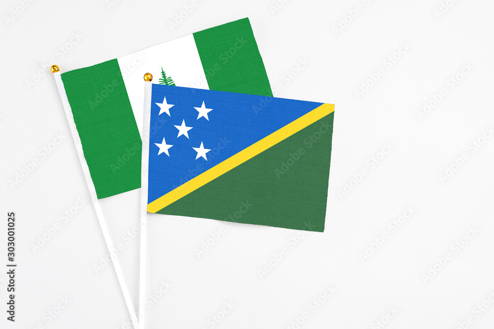Solomon Islands and Norfolk Island stick flags on white background. High quality fabric, miniature national flag. Peaceful global concept.White floor for copy space. Solomon Islands and Norfolk Island stick flags on white background. High quality fabric, miniature national flag. Peaceful global concept.White floor for copy space.