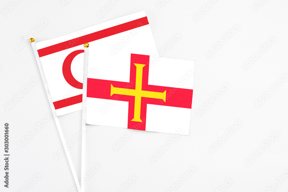Guernsey and Northern Cyprus stick flags on white background. High quality fabric, miniature national flag. Peaceful global concept.White floor for copy space.