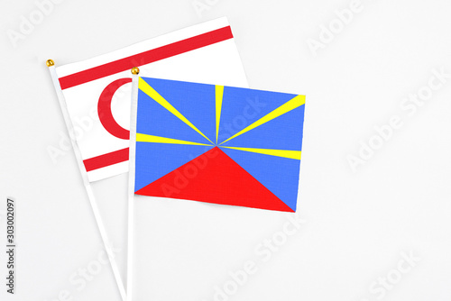 Reunion and Northern Cyprus stick flags on white background. High quality fabric, miniature national flag. Peaceful global concept.White floor for copy space.