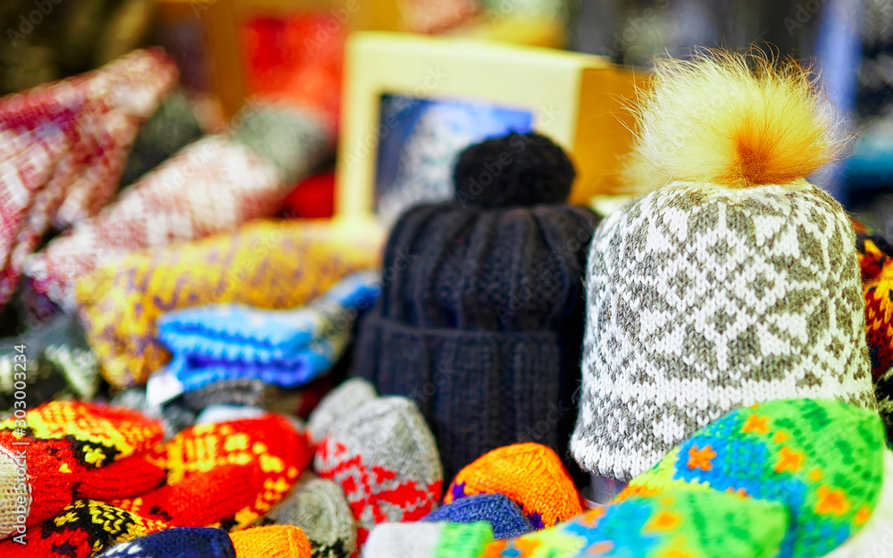 Warm hats and other knitted clothes in stalls at Christmas market in Riga of Latvia winter. Europe. Street Xmas and holiday fair in European city or town. Advent Decoration with Crafts Items on Bazaar