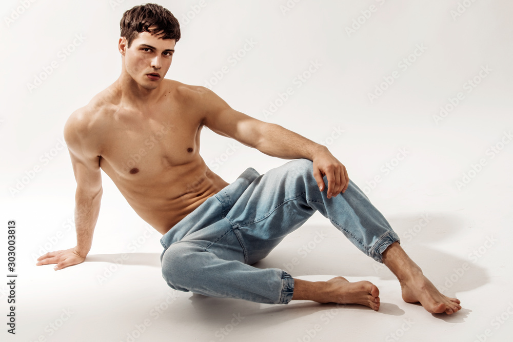 Muscle strong beautiful stripped male model in denim jeans on white isolated font background with shadow Muscle strong beautiful stripped male model in denim jeans on white isolated font background with shadow
