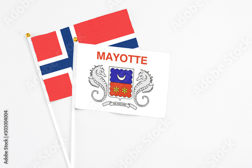 Mayotte and Norway stick flags on white background. High quality fabric, miniature national flag. Peaceful global concept.White floor for copy space.