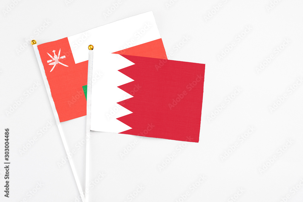 Bahrain and Oman stick flags on white background. High quality fabric, miniature national flag. Peaceful global concept.White floor for copy space. Bahrain and Oman stick flags on white background. High quality fabric, miniature national flag. Peaceful global concept.White floor for copy space.