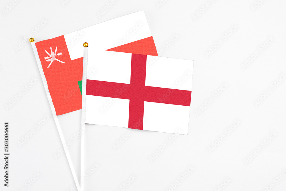 England and Oman stick flags on white background. High quality fabric, miniature national flag. Peaceful global concept.White floor for copy space.