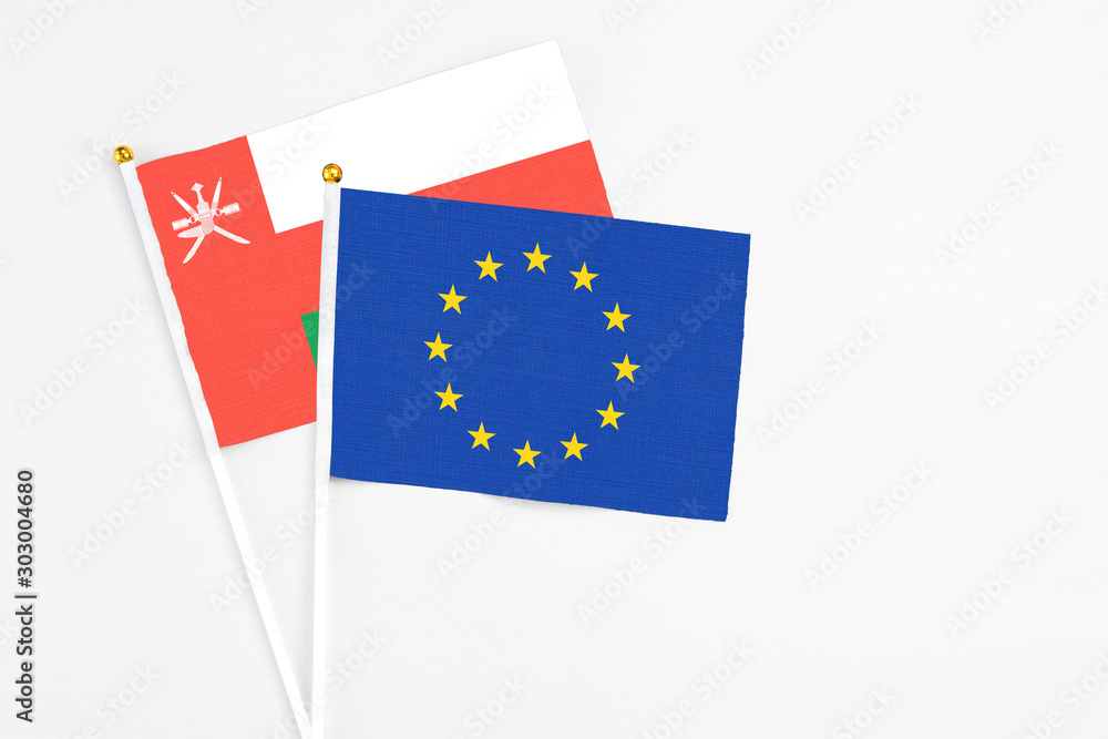 European Union and Oman stick flags on white background. High quality fabric, miniature national flag. Peaceful global concept.White floor for copy space. European Union and Oman stick flags on white background. High quality fabric, miniature national flag. Peaceful global concept.White floor for copy space.