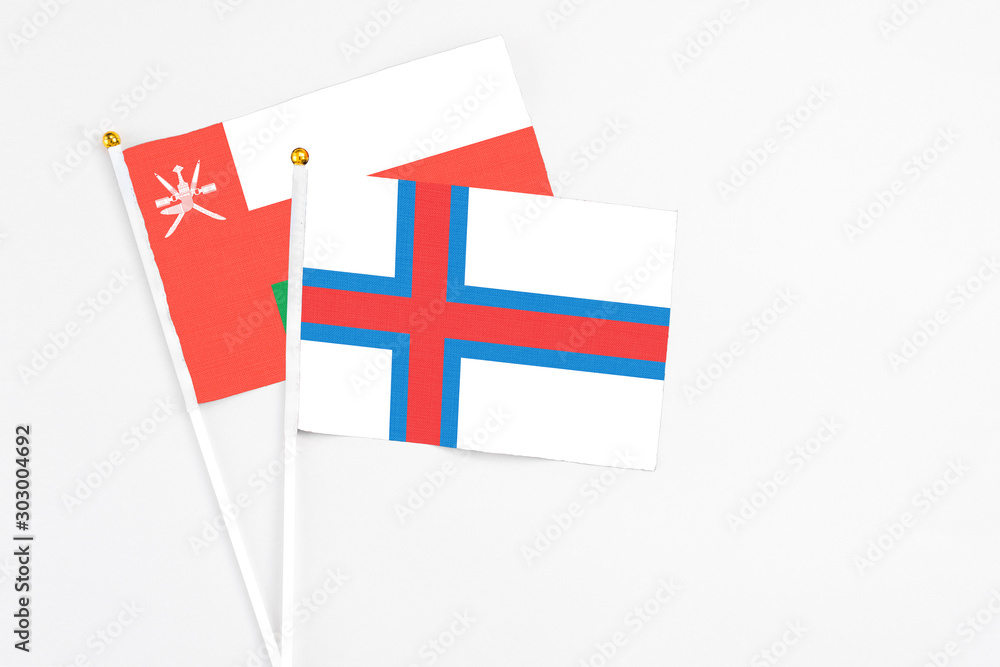 Faroe Islands and Oman stick flags on white background. High quality fabric, miniature national flag. Peaceful global concept.White floor for copy space.