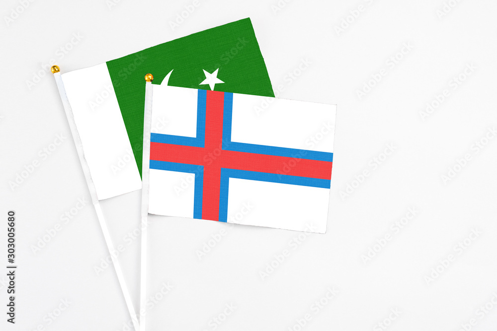 Faroe Islands and Pakistan stick flags on white background. High quality fabric, miniature national flag. Peaceful global concept.White floor for copy space.