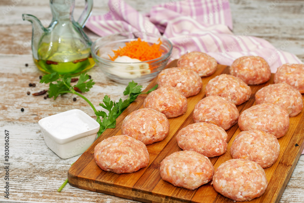 Fresh raw uncooked meatballs prepared for cooking in the kitchen, with some spices and olive oil.