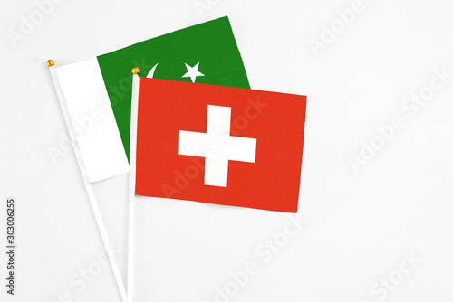 Switzerland and Pakistan stick flags on white background. High quality fabric, miniature national flag. Peaceful global concept.White floor for copy space. photo