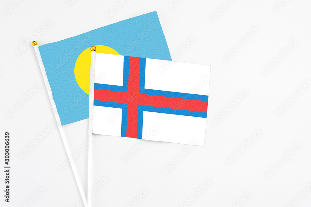 Faroe Islands and Palau stick flags on white background. High quality fabric, miniature national flag. Peaceful global concept.White floor for copy space.