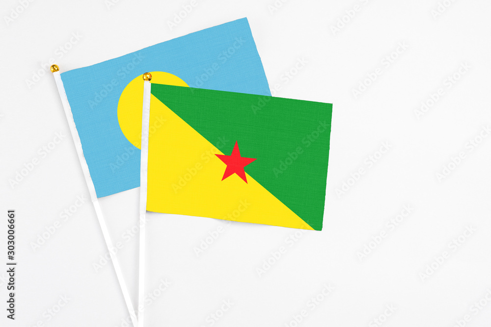 French Guiana and Palau stick flags on white background. High quality fabric, miniature national flag. Peaceful global concept.White floor for copy space. French Guiana and Palau stick flags on white background. High quality fabric, miniature national flag. Peaceful global concept.White floor for copy space.