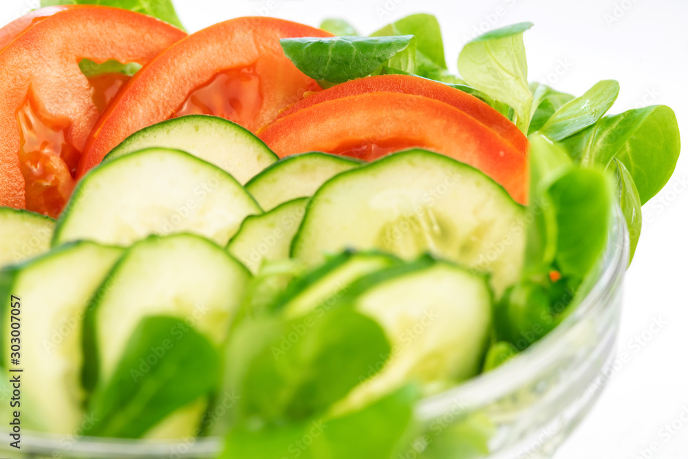 Vegetable summer salad made of cucumbers, tomatoes and salad in a glass bowl closeup on the white background. Healthy food isolated. Vegetable summer salad made of cucumbers, tomatoes and salad in a glass bowl closeup on the white background. Healthy food isolated.