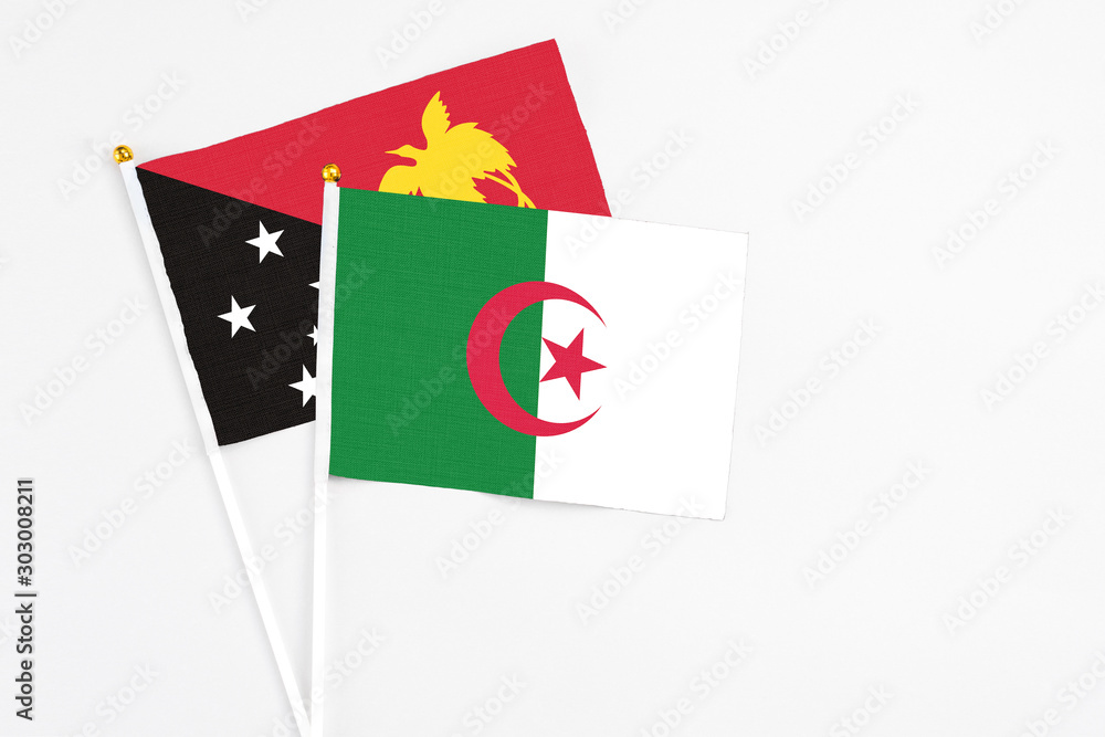 Algeria and Papua New Guinea stick flags on white background. High quality fabric, miniature national flag. Peaceful global concept.White floor for copy space. Algeria and Papua New Guinea stick flags on white background. High quality fabric, miniature national flag. Peaceful global concept.White floor for copy space.