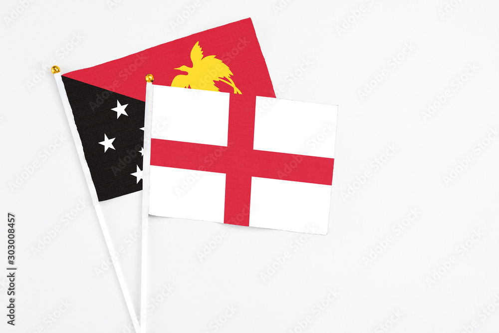 England and Papua New Guinea stick flags on white background. High quality fabric, miniature national flag. Peaceful global concept.White floor for copy space.