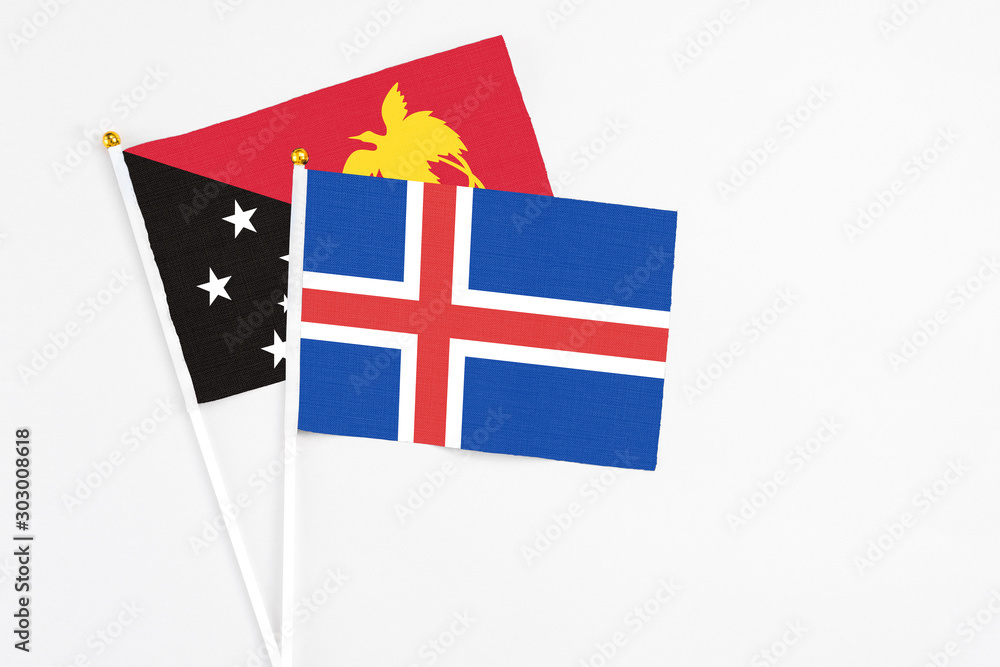 Iceland and Papua New Guinea stick flags on white background. High quality fabric, miniature national flag. Peaceful global concept.White floor for copy space.