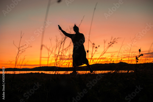 silhouette of a girl dancing on the background of a beautiful sunset © Oksy001