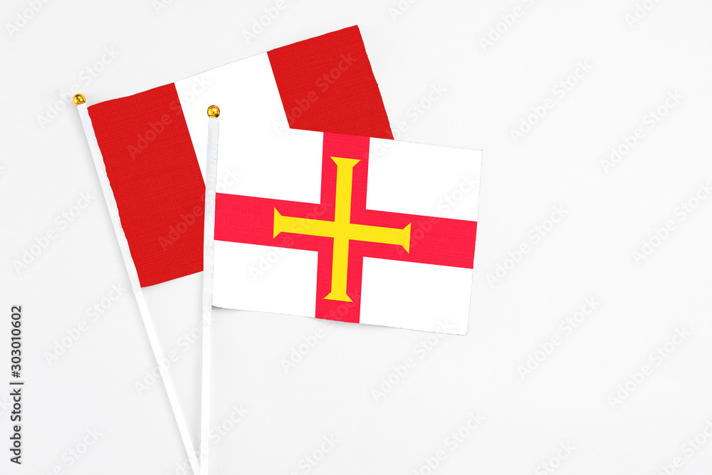 Guernsey and Peru stick flags on white background. High quality fabric, miniature national flag. Peaceful global concept.White floor for copy space.