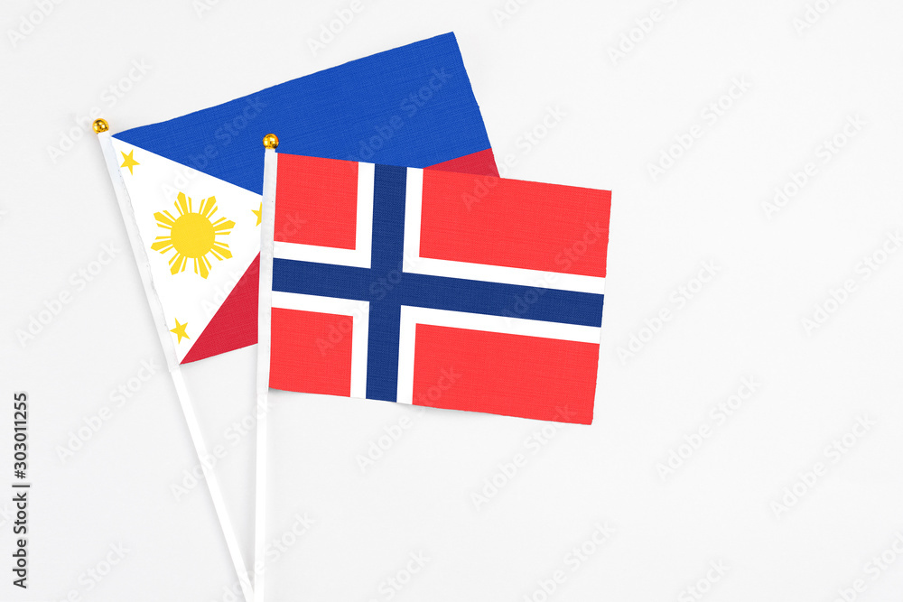 Bouvet Islands and Philippines stick flags on white background. High quality fabric, miniature national flag. Peaceful global concept.White floor for copy space.
