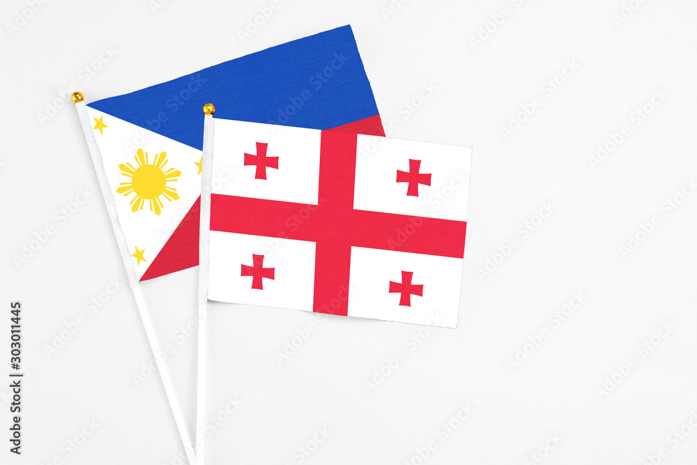 Georgia and Philippines stick flags on white background. High quality fabric, miniature national flag. Peaceful global concept.White floor for copy space.