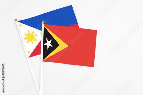 East Timor and Philippines stick flags on white background. High quality fabric, miniature national flag. Peaceful global concept.White floor for copy space.